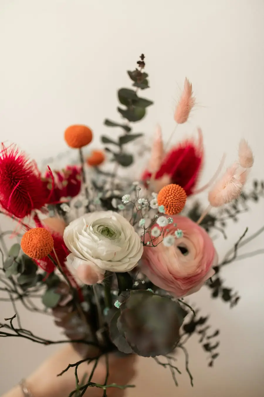 Wild boeket met ranonkels, oranje craspedia en eucalyptus